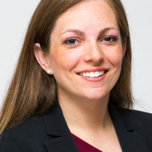 Smiling woman with long brown hair and pearl earrings